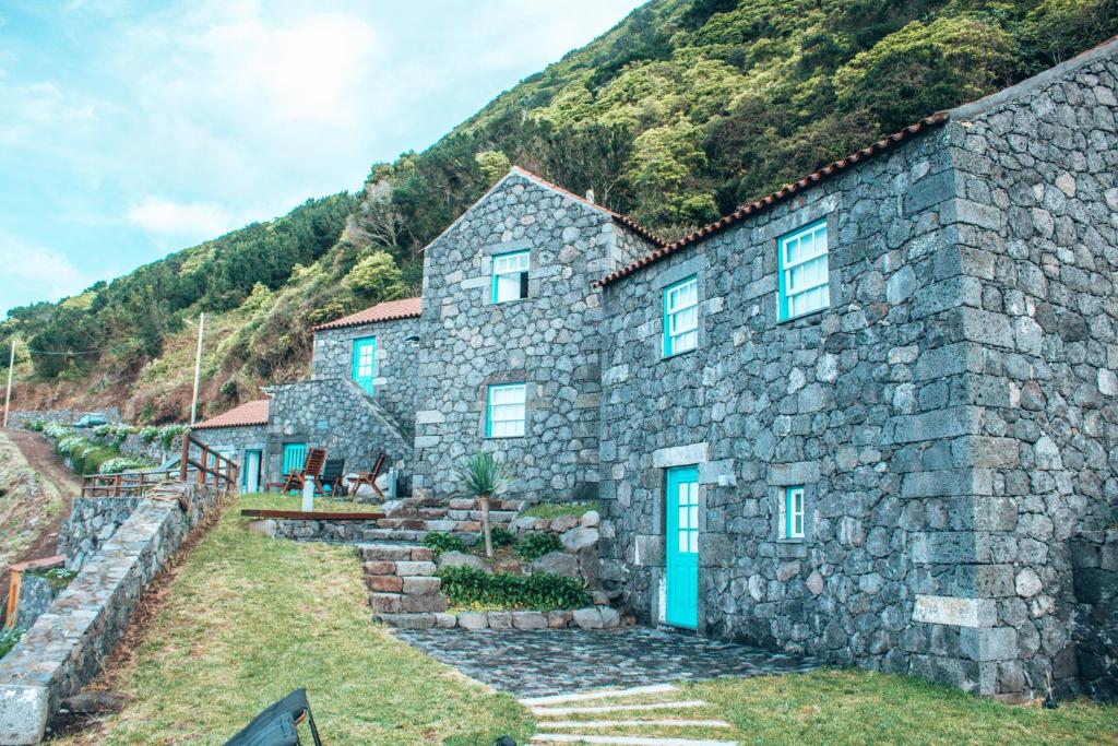 una casa in pietra con una porta blu di fronte a una montagna di Abrigo da Cascata - Casas de Campo - São Jorge a Calheta