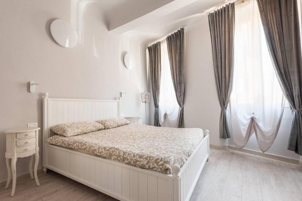 ein weißes Schlafzimmer mit einem Bett und zwei Fenstern in der Unterkunft Happy Florence San Niccolò n.1 in Florenz