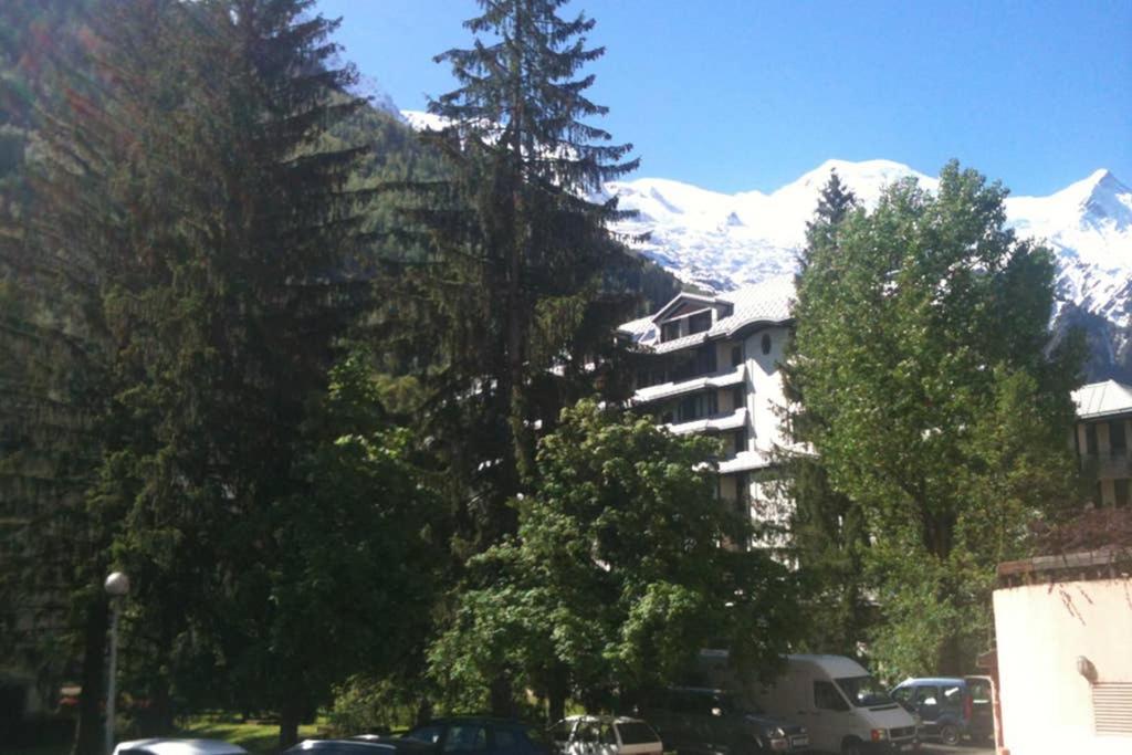 a parking lot with a building and trees and mountains at Appartement Chamonix - Vue Mont Blanc in Chamonix
