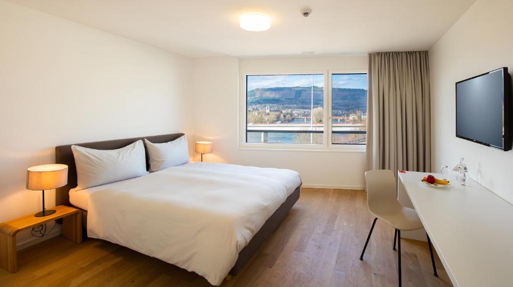 una camera d'albergo con un grande letto bianco e una scrivania di Motel Rheinfels Park a Stein