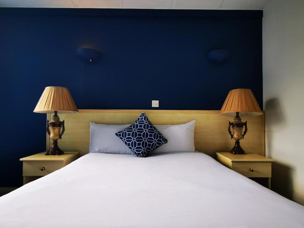 a bedroom with a large white bed with two lamps at Castle Hotel in Merthyr Tydfil