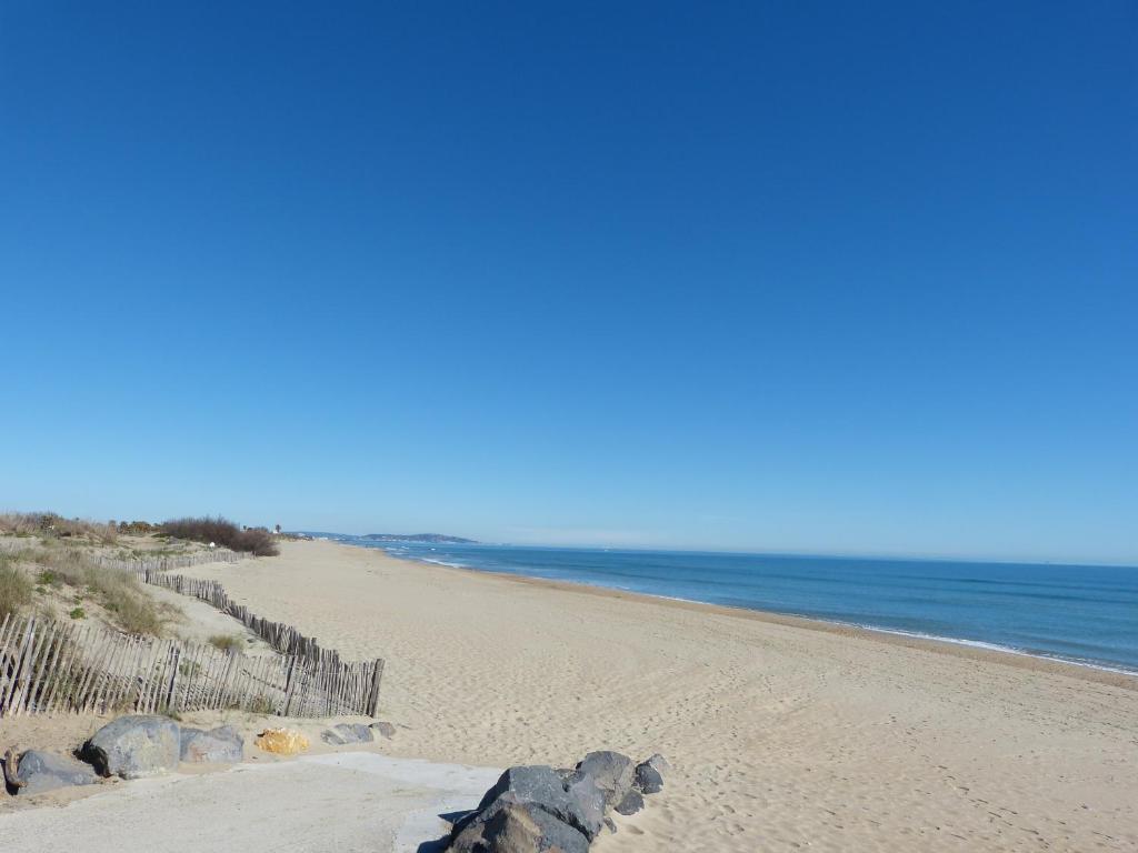 une plage de sable avec une clôture et l'océan dans l'établissement Blue Sea Vue mer - Village naturiste Héliopolis, au Cap d'Agde