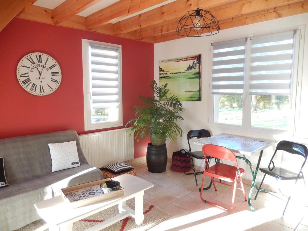 ein Wohnzimmer mit einem Sofa und einer Uhr an der Wand in der Unterkunft Chambre D'Hôtes Les Jards in Bressuire