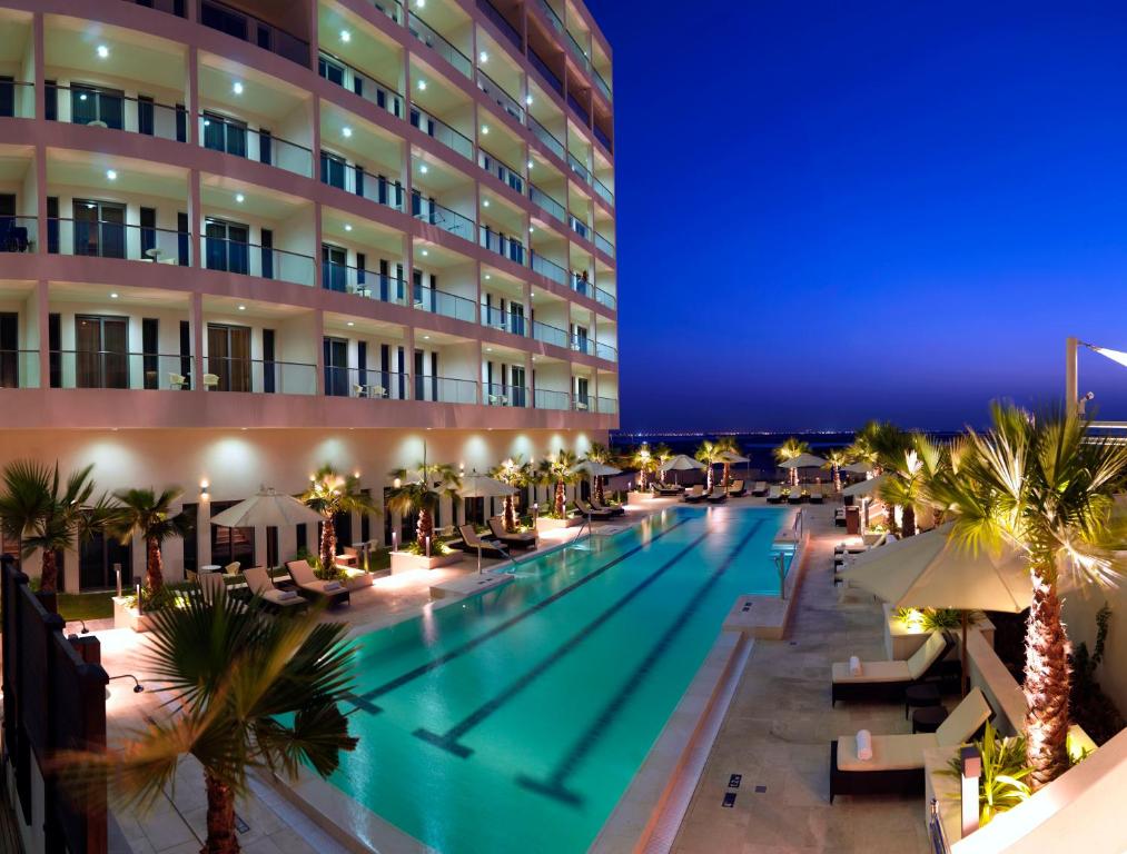 una piscina frente a un hotel por la noche en Staybridge Suites Yas Island Abu Dhabi, an IHG Hotel, en Abu Dabi