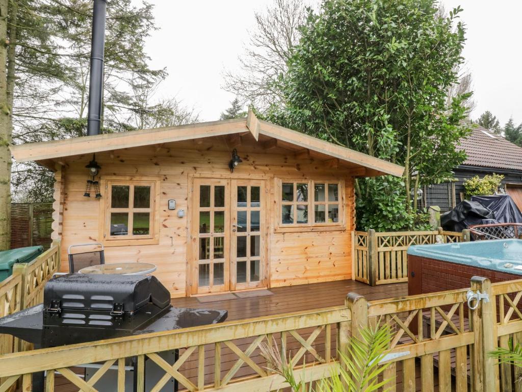 a wooden cabin with a grill on a deck at Someplace Else in Diss