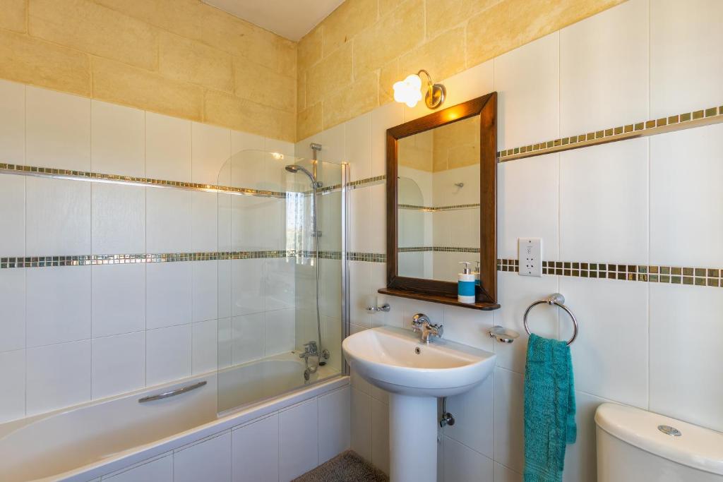 a bathroom with a sink and a mirror and a tub at Ghajn Damma in Xagħra