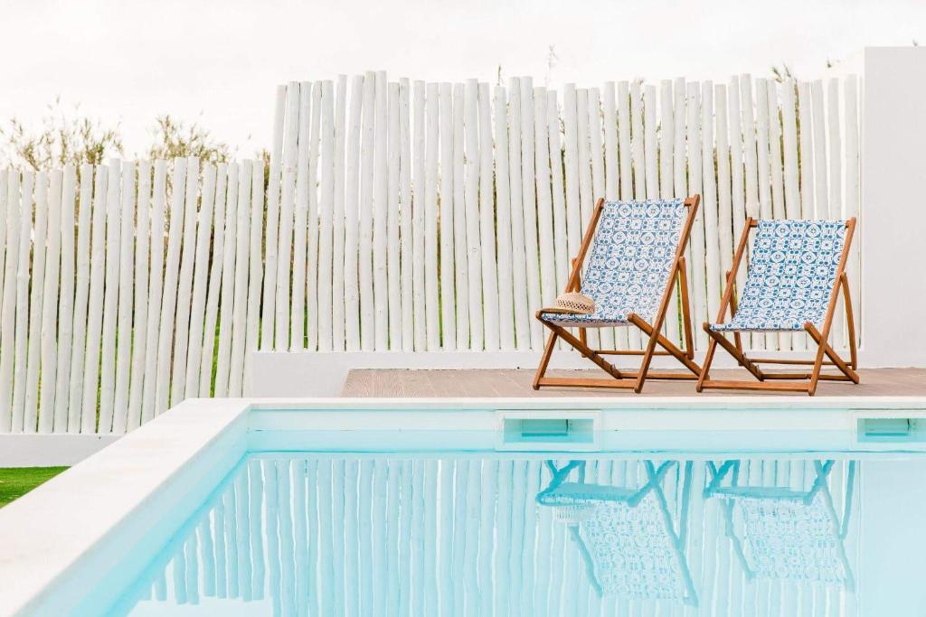 two chairs sitting next to a swimming pool at Quinta das Alfazemas in Ericeira