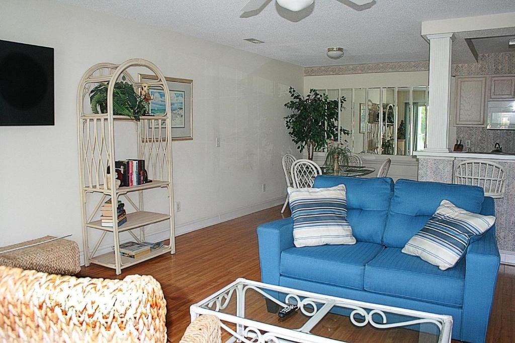 a living room with a blue couch and a table at Brunswick Plantation Resort and Golf Condo 805M with Full Kitchen in Calabash