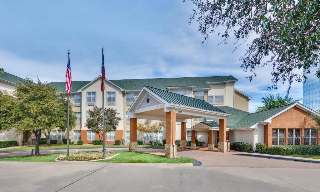 Um edifício com uma bandeira americana à frente. em Candlewood Suites Dallas Market Center-Love Field, an IHG Hotel em Dallas