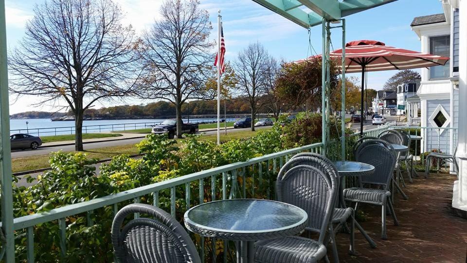 un patio con mesas, sillas y una sombrilla en Harborview Inn en Gloucester