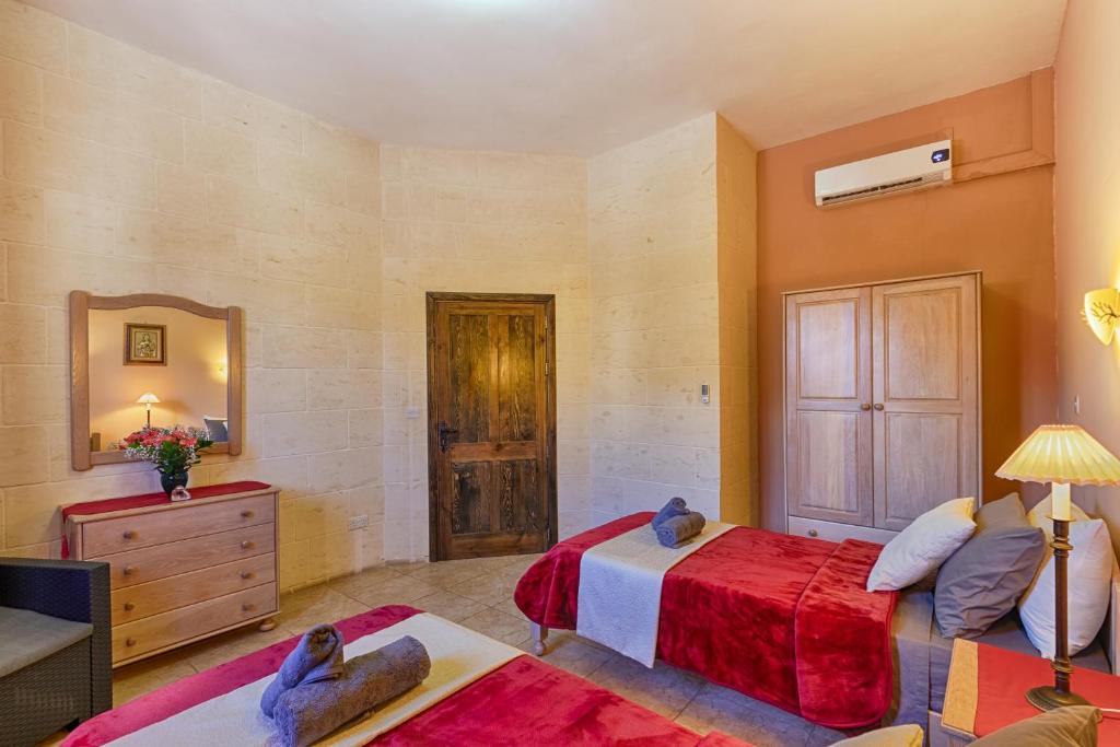 a bedroom with a bed and a dresser and a mirror at Ghajn Damma in Xagħra