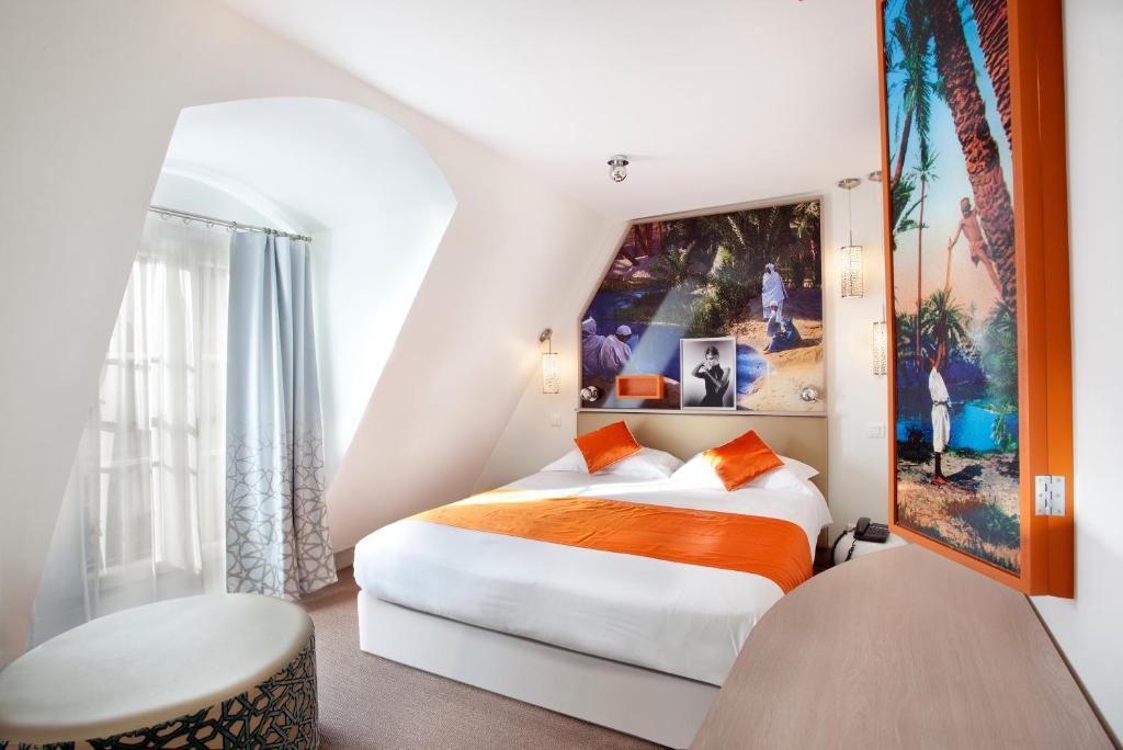 Habitación de hotel con cama con manta naranja en Hôtel Mayet en París