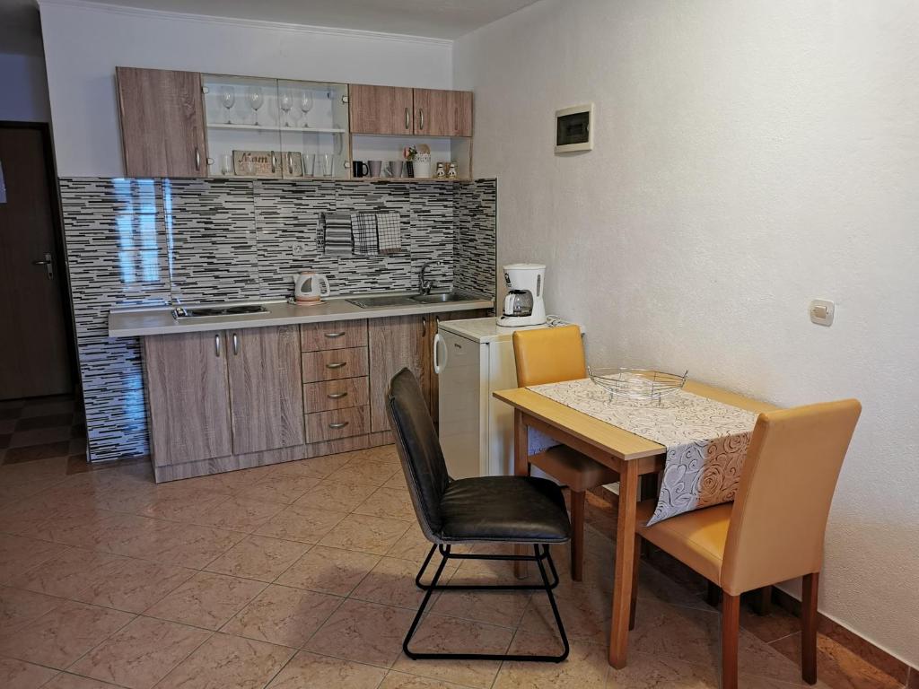 a kitchen with a table and chairs and a kitchen with a refrigerator at Apartmani Prova 4 in Tisno