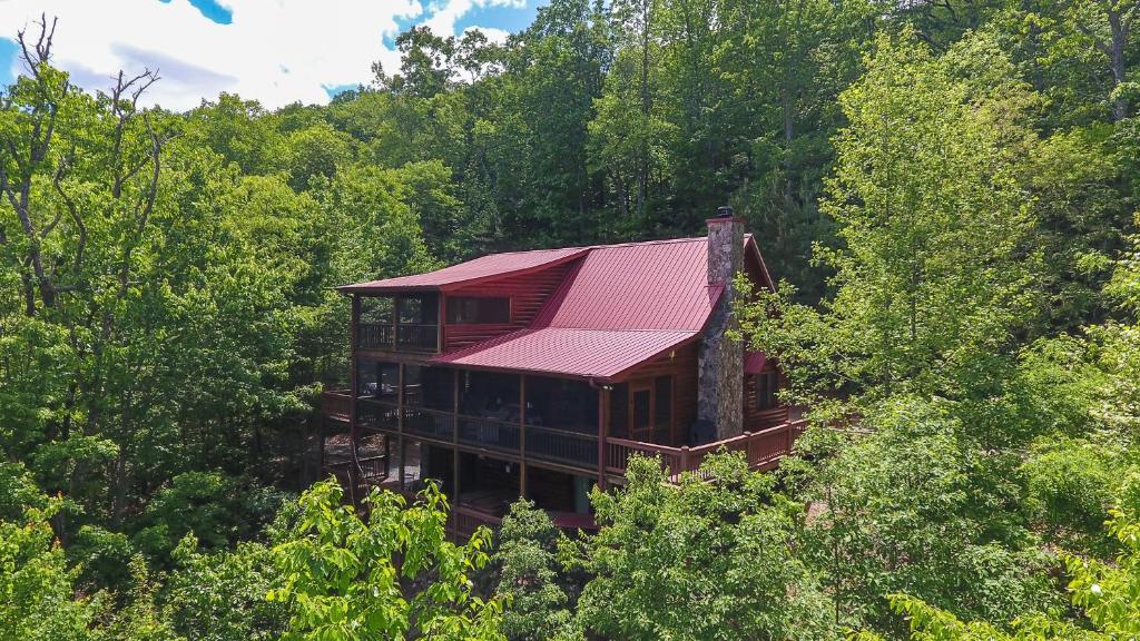 a house with a red roof in the middle of trees at CABIN TIME - When you need to relax and unwind a visit to Cabin Time is what you need! in Mineral Bluff