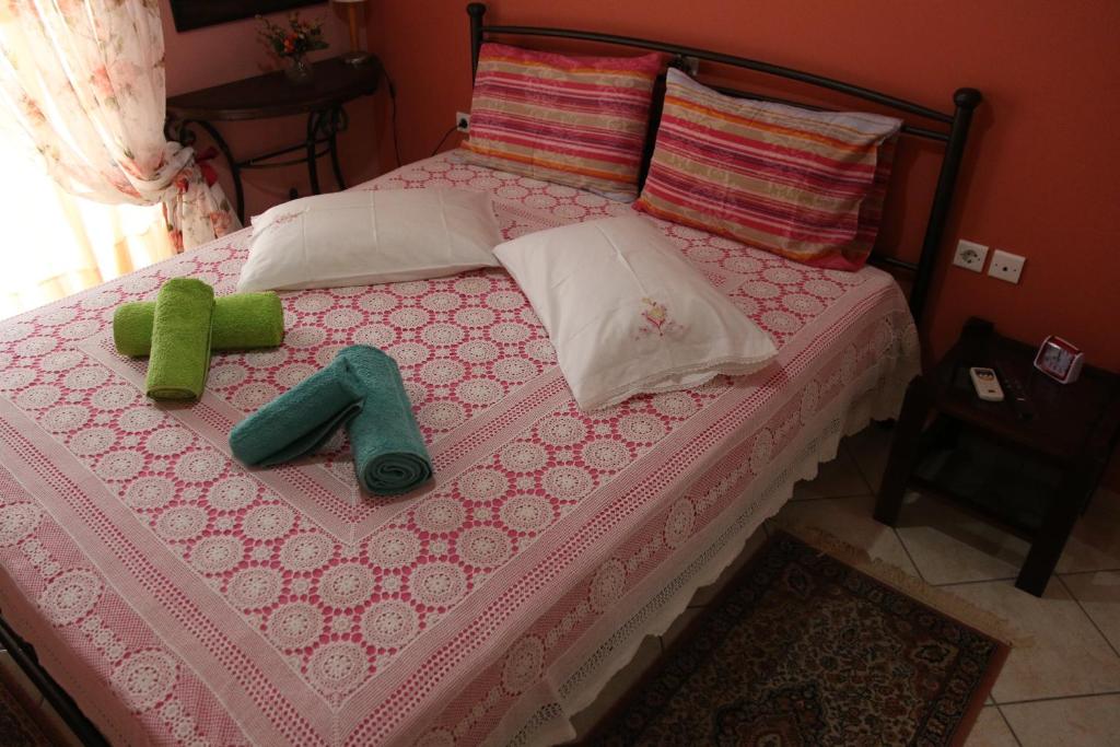a pink bed with two green objects on it at Nafpaktos Apartments in Nafpaktos