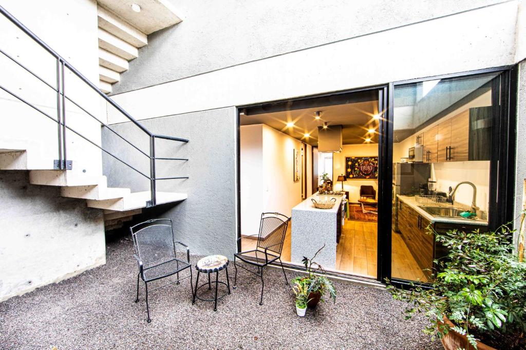 einen Balkon mit Stühlen, eine Küche und eine Treppe in der Unterkunft Modern & Renovated Apartment with Private Patio in Tacuba - Legaria in Mexiko-Stadt