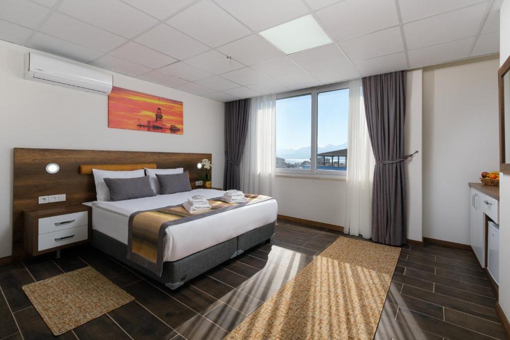 アンタルヤにあるGrand Gulluk Hotel & Spaのベッドと大きな窓が備わるホテルルームです。