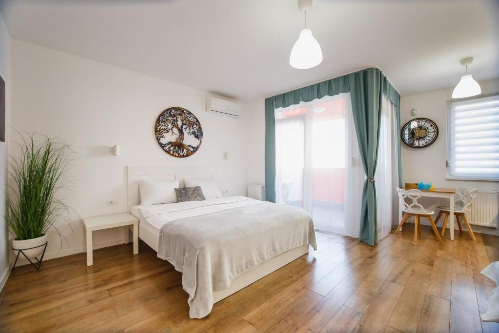 een slaapkamer met een wit bed en een groot raam bij Enjoy Time in Central Oradea in Oradea