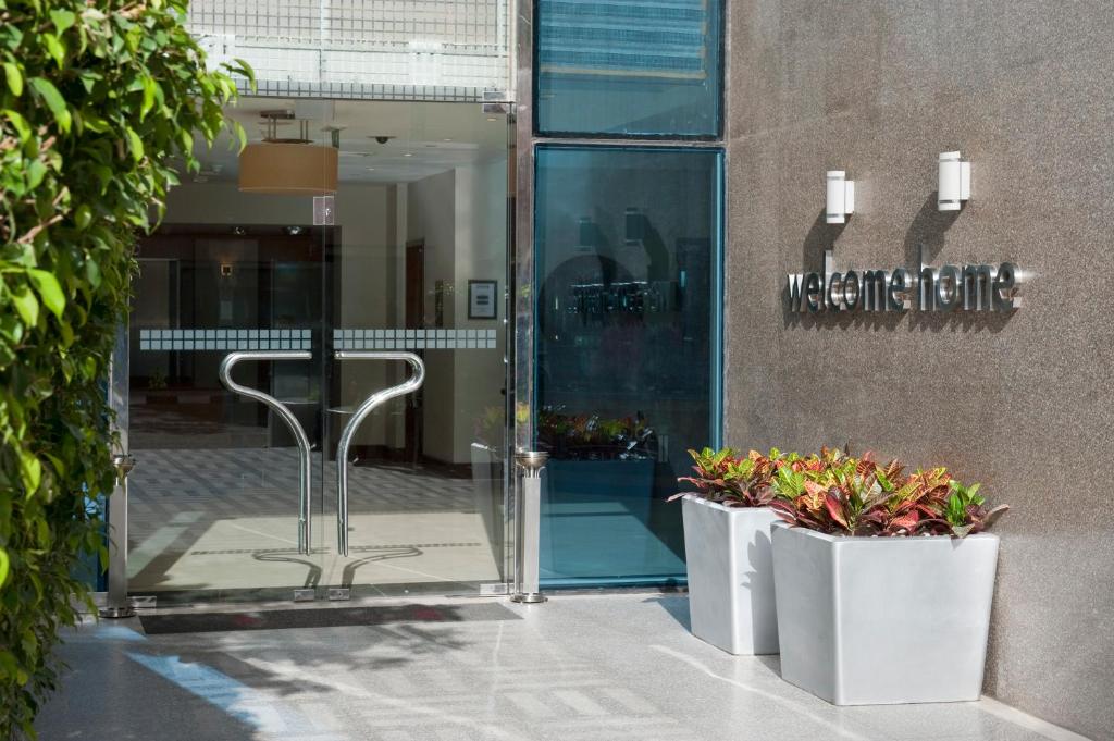 une porte en verre d'un bâtiment avec deux plantes en pot dans l'établissement Staybridge Suites & Apartments - Citystars, an IHG Hotel, au Caire