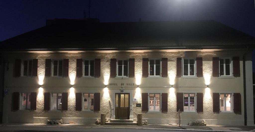 a white building with lights on it at night at Hôtel de Ville in Les Verrières