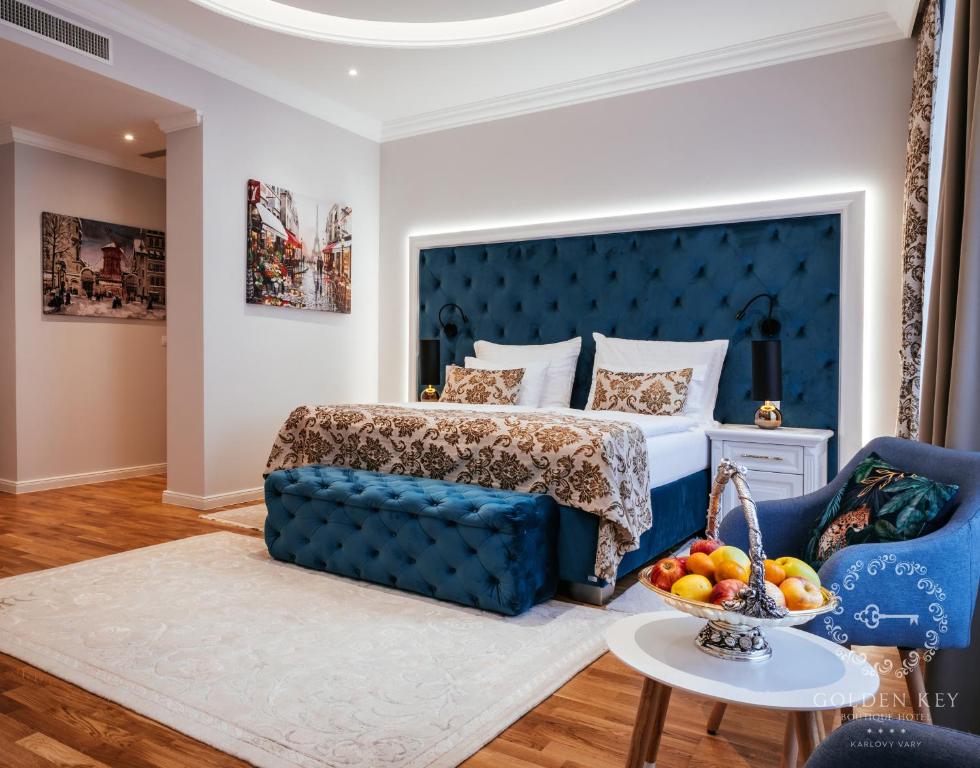 a bedroom with a blue bed and a table with a bowl of fruit at Golden Key Boutique Hotel in Karlovy Vary