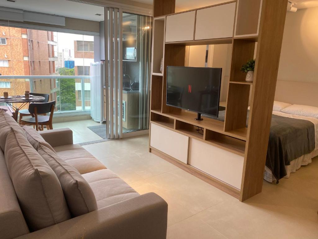 uma sala de estar com um sofá e uma televisão de ecrã plano em SUA CASA NA VILA MADALENA em São Paulo