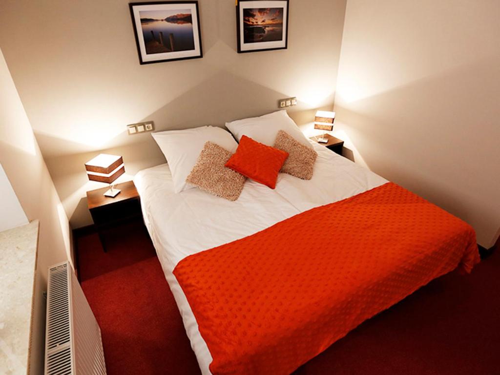 a bedroom with a bed with an orange blanket at Hotel Otoliński in Płock