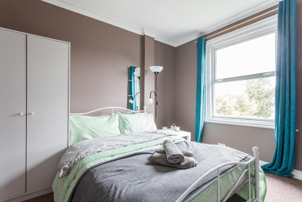 1 dormitorio con 1 cama con cortinas azules y ventana en Shirley House 1, Guest House, Self Catering, Self Check in with smart locks, use of Fully Equipped Kitchen, Walking Distance to Southampton Central, Excellent Transport Links, Ideal for Longer Stays, en Southampton