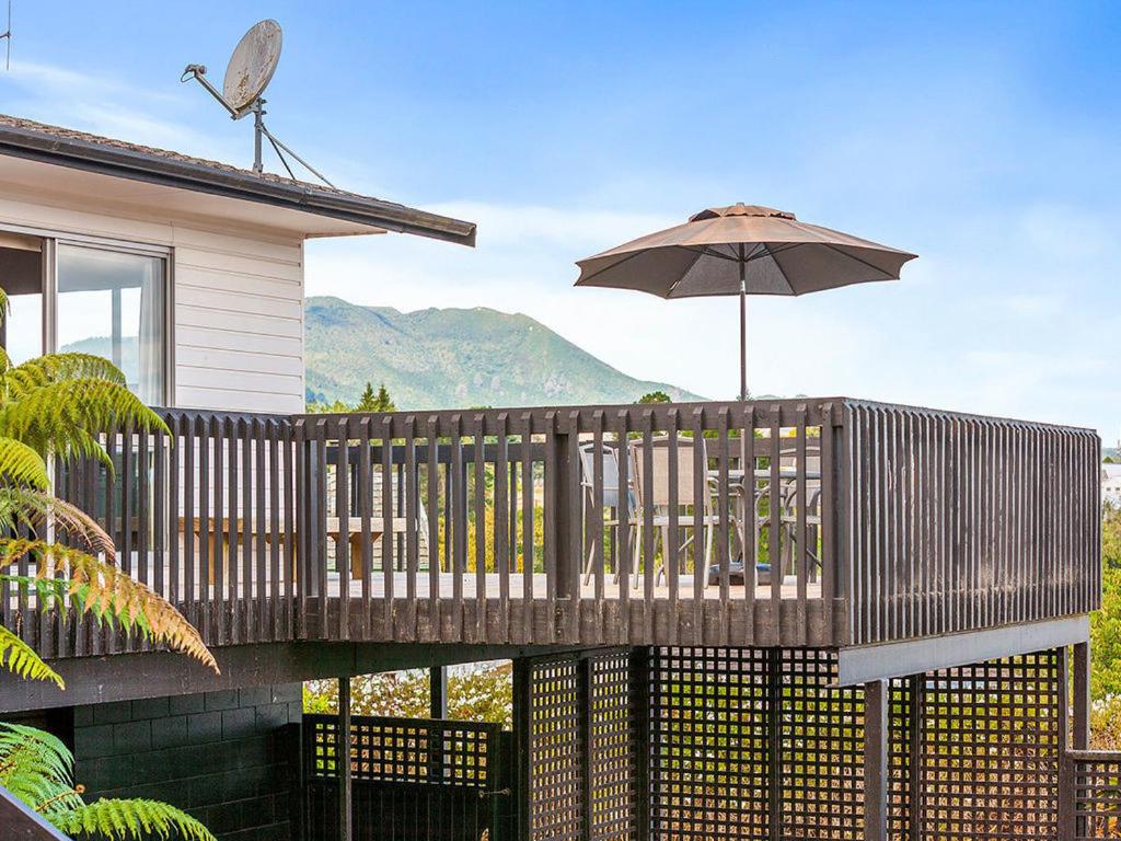 a wooden deck with an umbrella and a table at Taupo Panorama - Lake Taupo Holiday Home in Taupo
