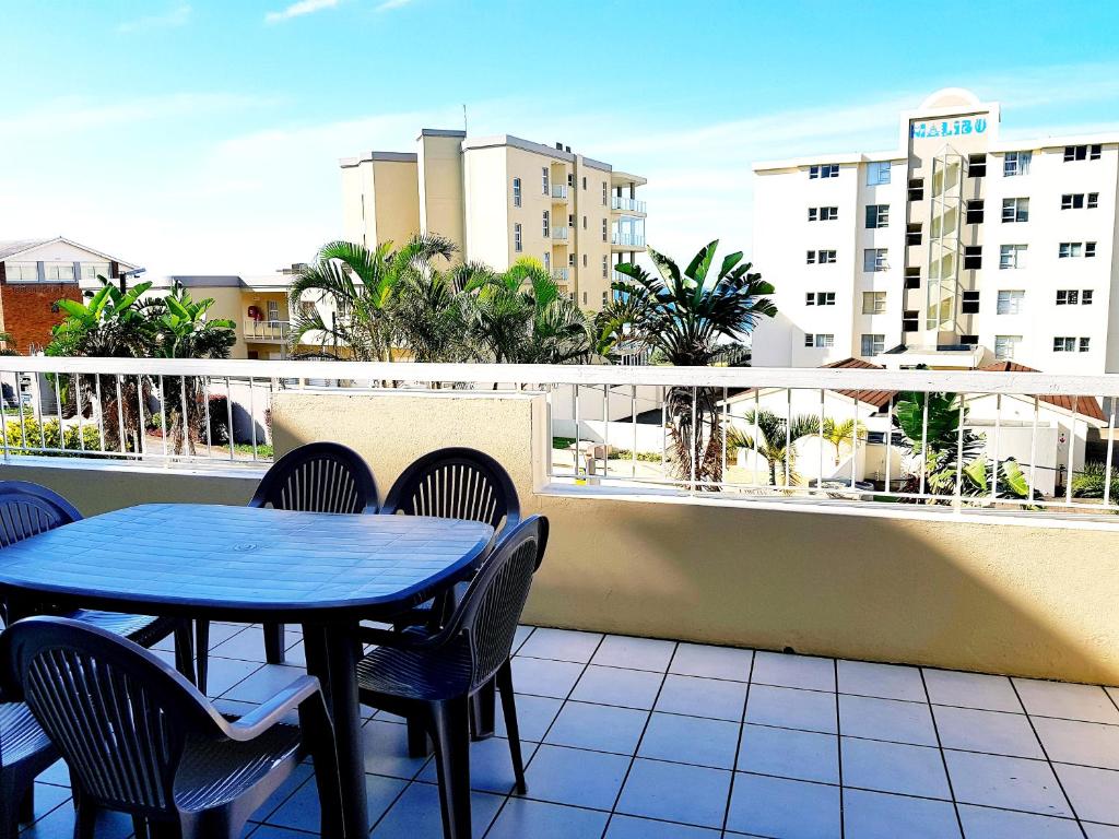 patio ze stołem i krzesłami na balkonie w obiekcie Sunset Cove 2 w mieście Margate