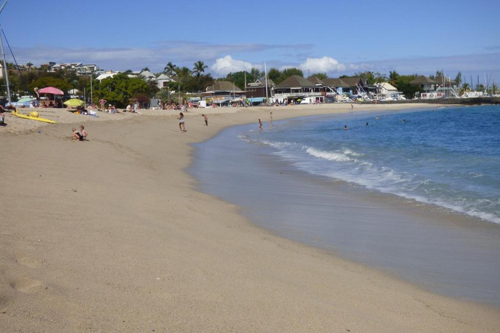 a beach with people sitting on the sand and the ocean at CASE BEAOEL in Saint-Gilles les Bains