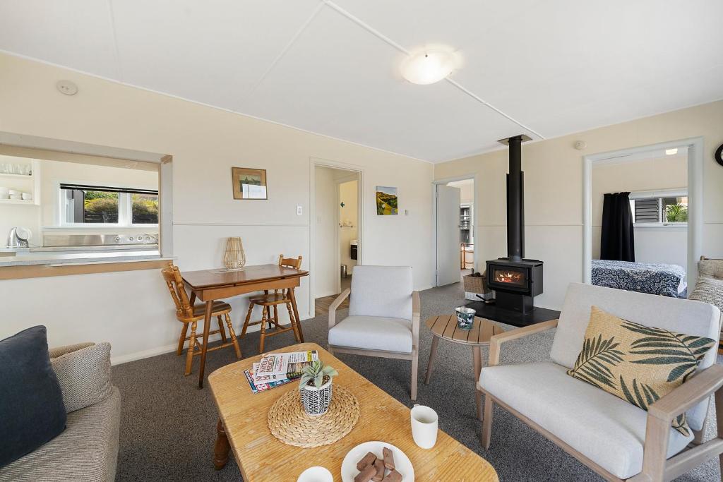 a living room with a couch and a stove at The Green Trout - Paraparaumu Beach Holiday Home in Paraparaumu Beach