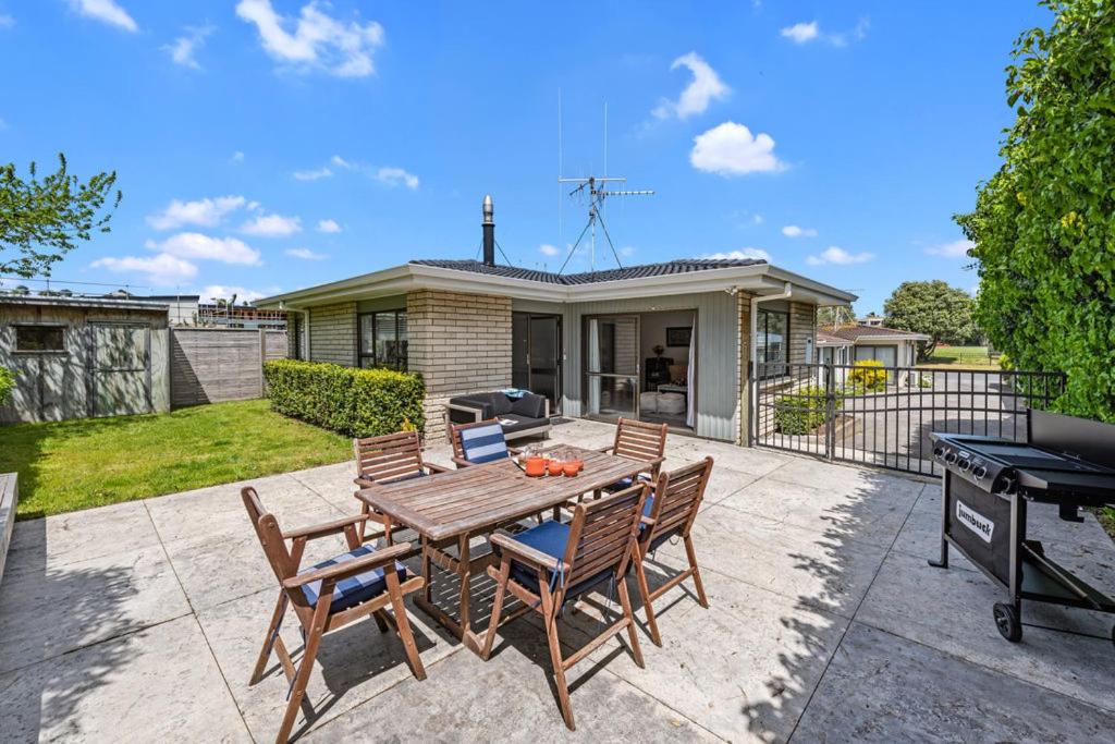 a patio with a wooden table and chairs and a grill at Bach Relax - Mt Maunganui Holiday Home in Mount Maunganui