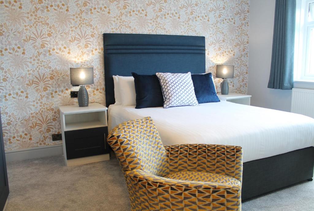 a bedroom with a large bed and a chair at The Pines Hotel in Swanage