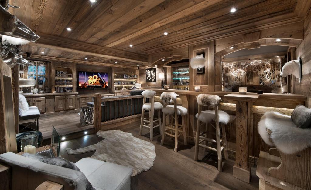 a bar with stools in a room with wooden walls at Chalet Makalu in Courchevel