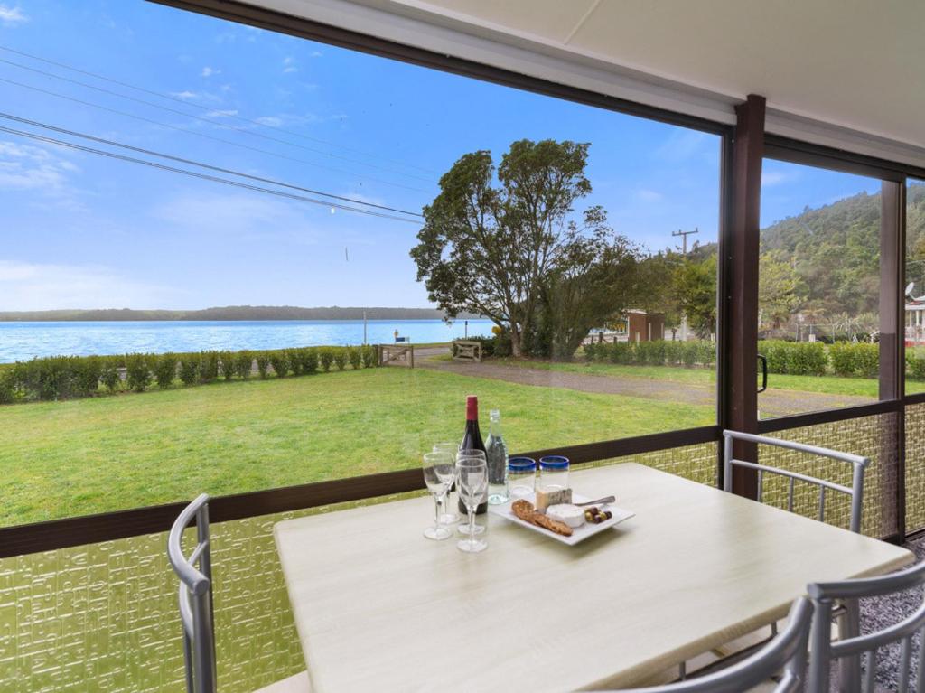a table with a bottle of wine and glasses on it at Relax Lakeside - Lake Rotoiti Bach in Rotoiti