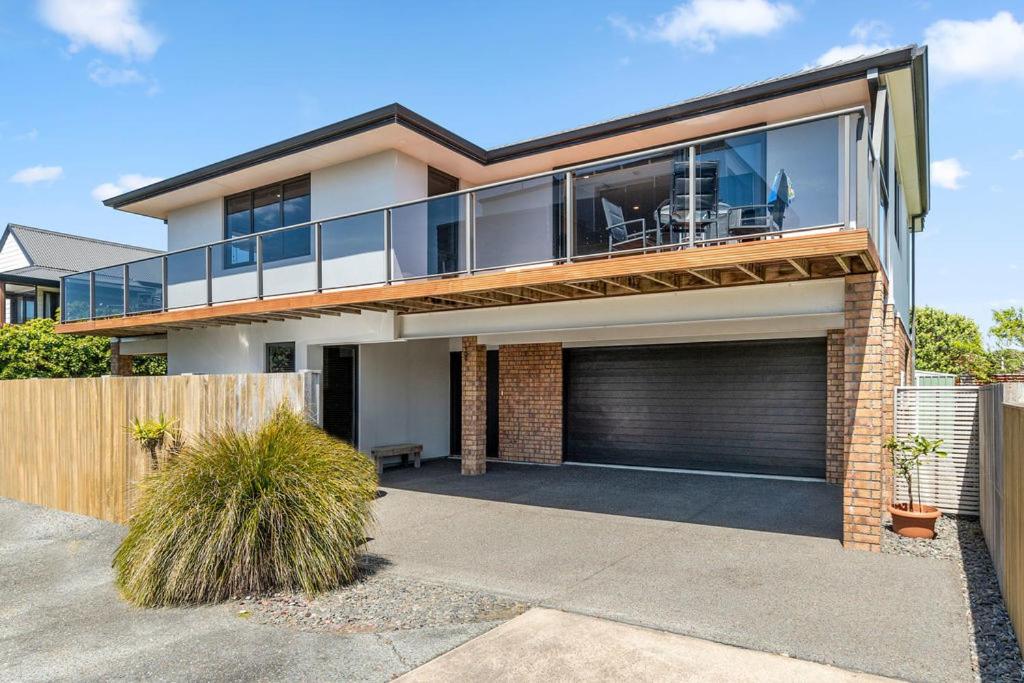 a house with a balcony on top of it at Sparkling Ocean Views - Papamoa Holiday House in Papamoa