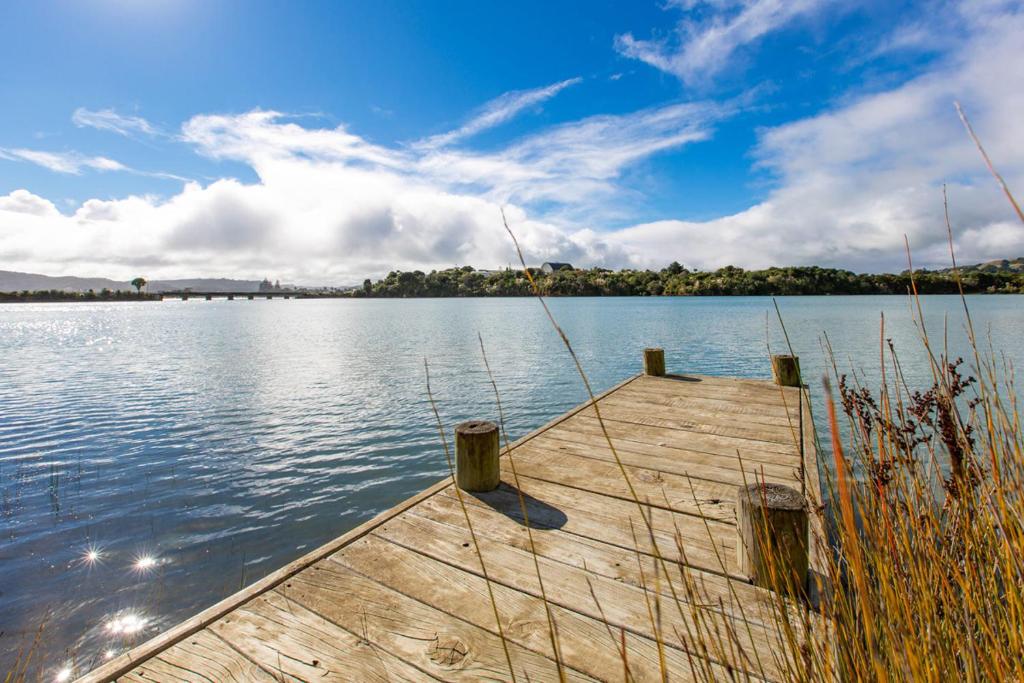 a wooden dock on a large body of water at Waterfront Bach - Raglan Bach in Raglan