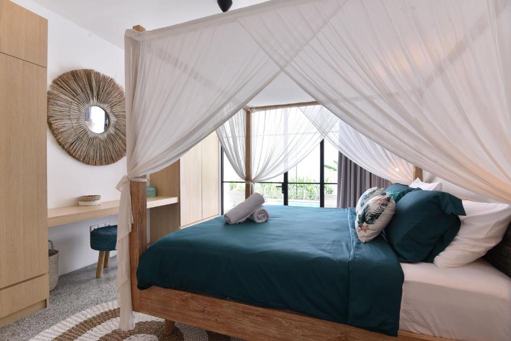 a bedroom with a canopy bed with a window at Villa Verde close to Finns Beach Club in Canggu