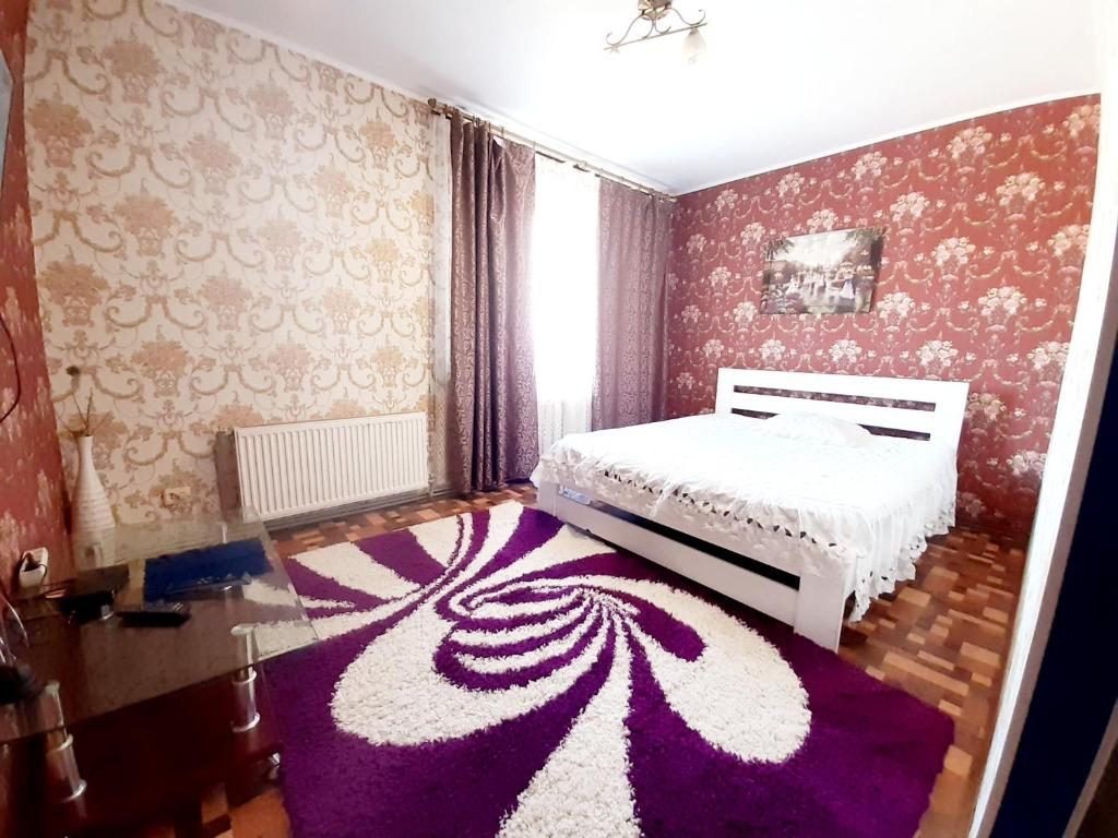 a bedroom with a white bed and a purple rug at Yanovskogo 3k in Kropyvnytskyi