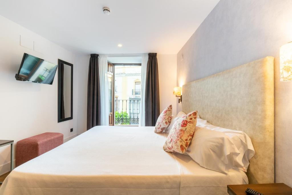 Habitación de hotel con cama y ventana en Suites San Pablo, en Sevilla