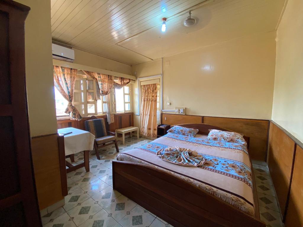 Hotel Levy's في بانغي: غرفة نوم بسرير وطاولة وكراسي