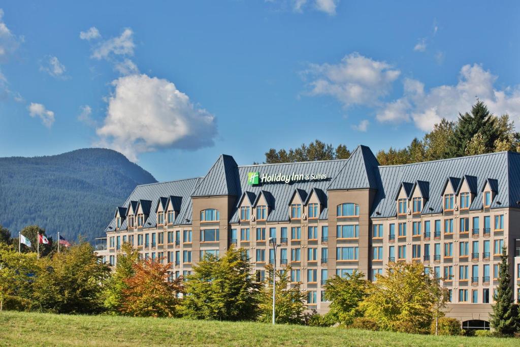 a large building with a mountain in the background at Holiday Inn & Suites North Vancouver, an IHG Hotel in North Vancouver