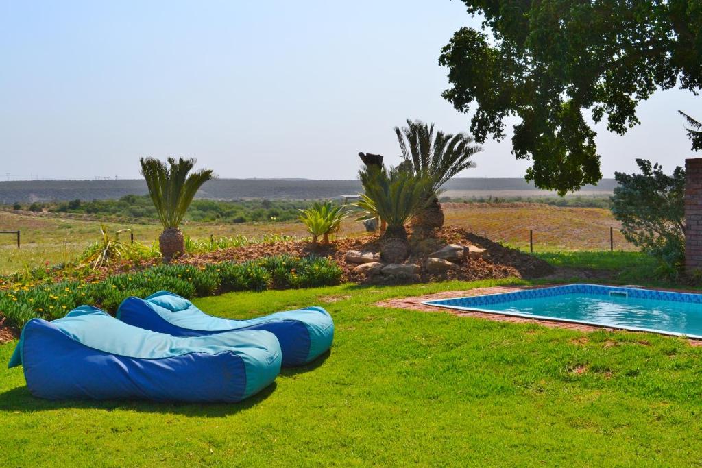 una balsa inflable azul está en la hierba junto a una piscina en The Kraal Addo en Addo