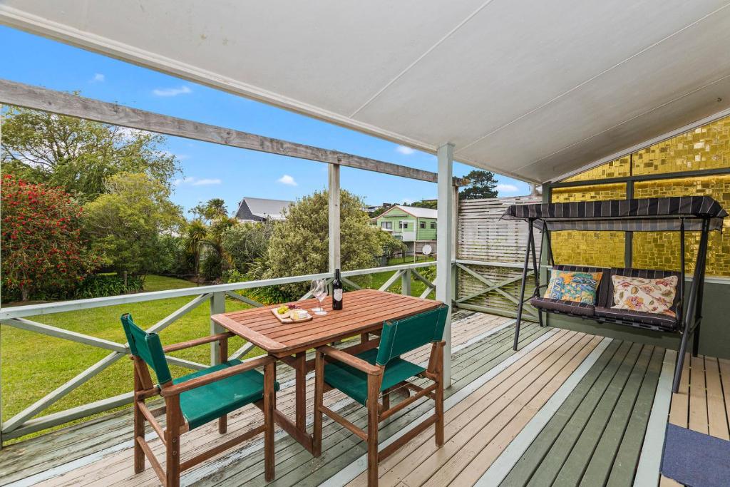 a deck with a wooden table and chairs on it at The Taranui Cottage - Mangawhai Heads Holiday Home in Mangawhai