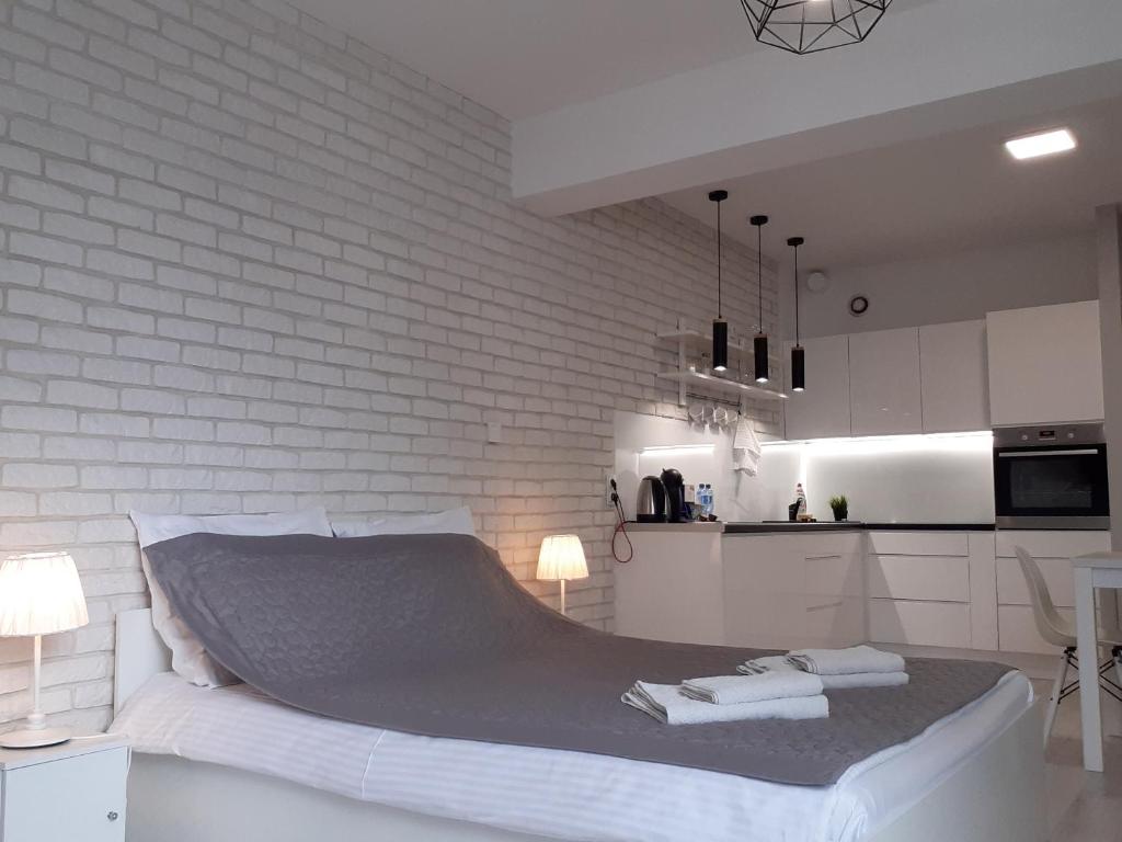 カトヴィツェにあるActivTower Apartamentの白レンガの壁、ベッド付きのベッドルーム1室