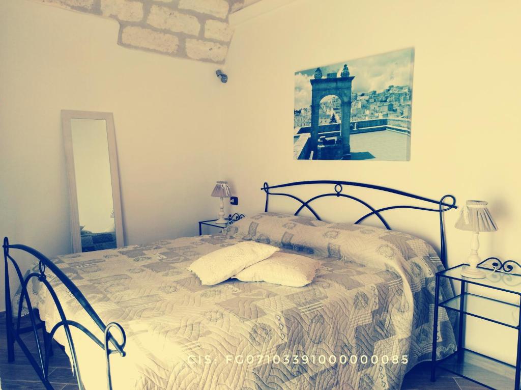 モンテ・サンタンジェロにあるLe Casette nel Rioneのベッドルーム1室(ベッド1台付)が備わります。壁に絵が飾られています。