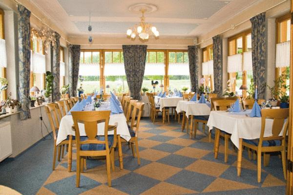 a dining room with tables and chairs and a chandelier at Haus Waldesruh in Hollnich