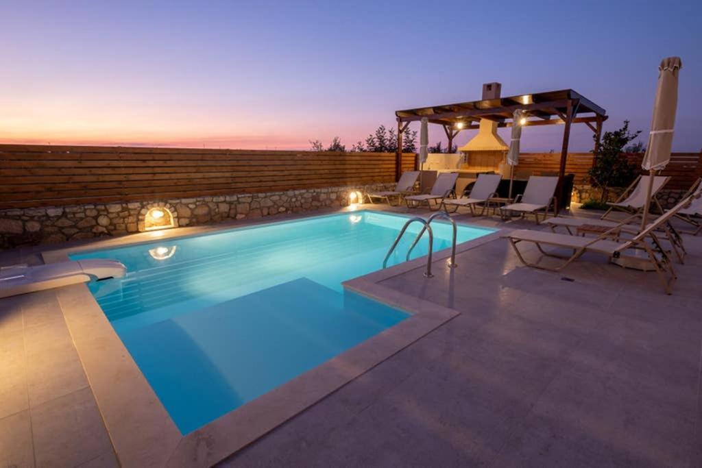 basen z krzesłami i stołem na patio w obiekcie Prinos Oasis Twin Villas II w mieście Prínos