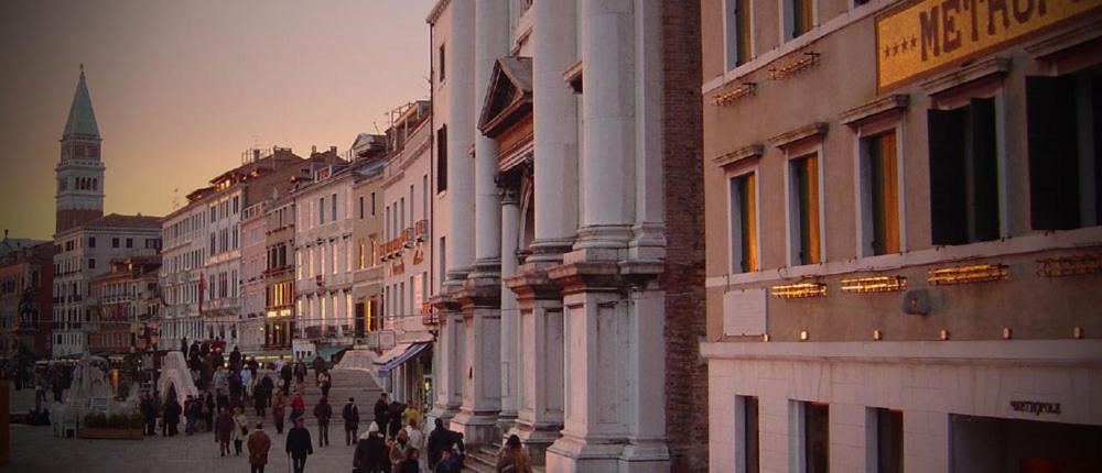 a group of people walking down a street with buildings at Hotel Metropole Venezia in Venice